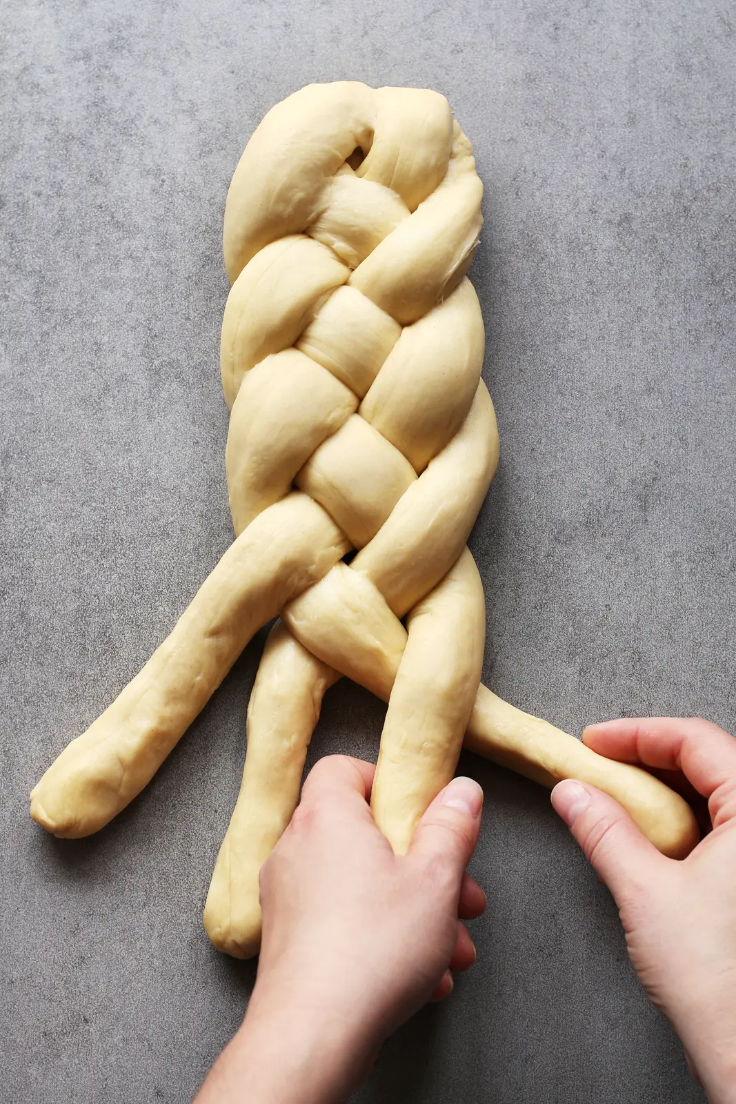 Female hands braiding bread dough.