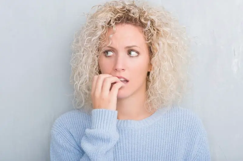 woman biting nails, looking stressed and nervous
